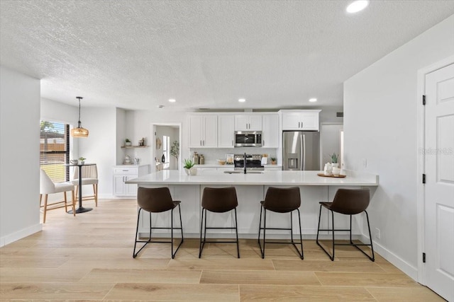 kitchen with a sink, light countertops, a breakfast bar area, and stainless steel appliances