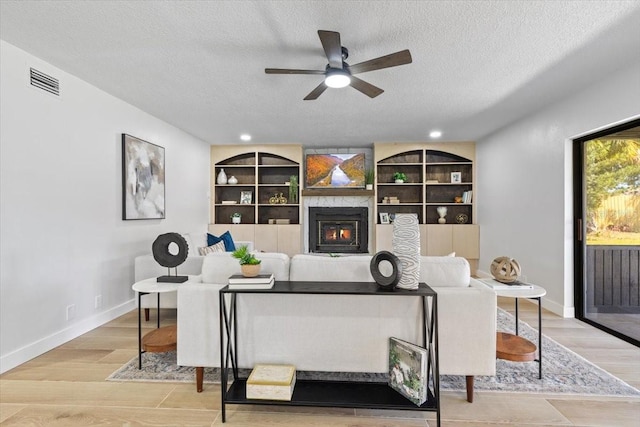 living room featuring visible vents, ceiling fan, baseboards, and a textured ceiling