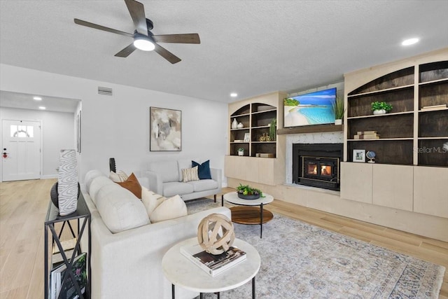 living room with visible vents, ceiling fan, wood finished floors, and a textured ceiling