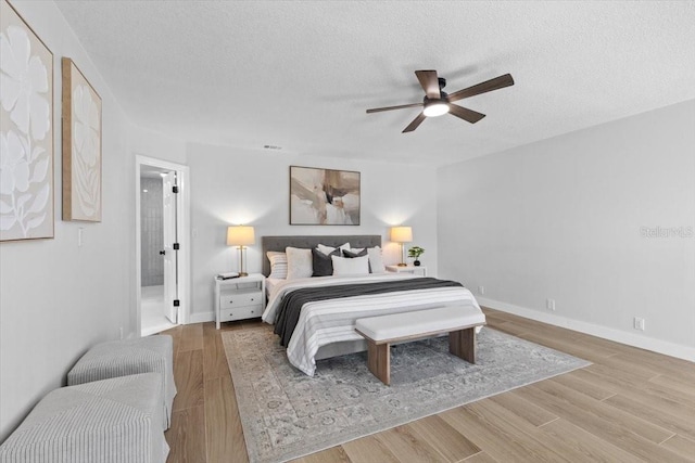 bedroom featuring a textured ceiling, wood finished floors, baseboards, and a ceiling fan