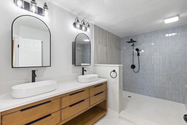 full bathroom with a textured ceiling, double vanity, and a sink