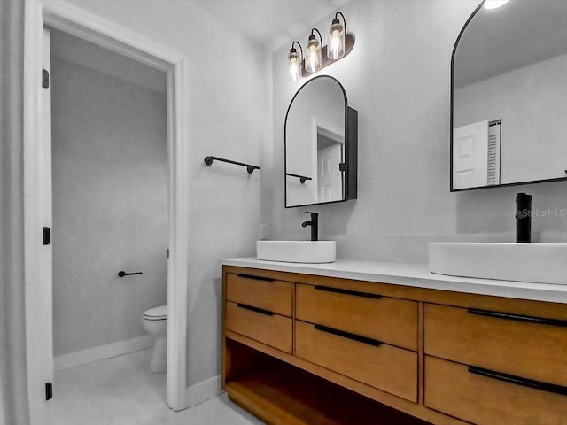 bathroom with double vanity, baseboards, a sink, and toilet