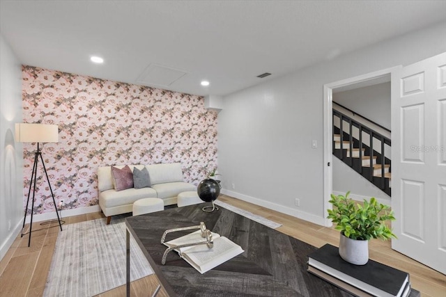 living room featuring visible vents, baseboards, wood finished floors, and wallpapered walls