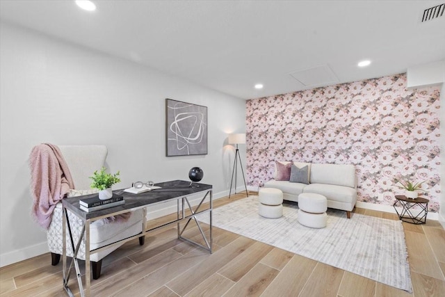 sitting room with visible vents, baseboards, an accent wall, and wallpapered walls