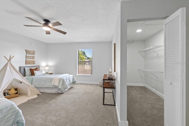 bedroom with carpet, baseboards, a textured ceiling, and a ceiling fan