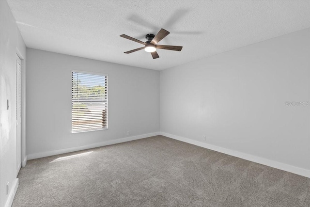 carpeted empty room with a textured ceiling, baseboards, and a ceiling fan