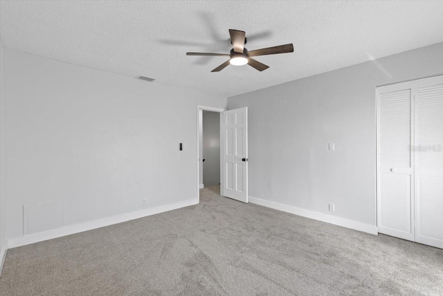 unfurnished bedroom featuring a textured ceiling, visible vents, baseboards, and carpet