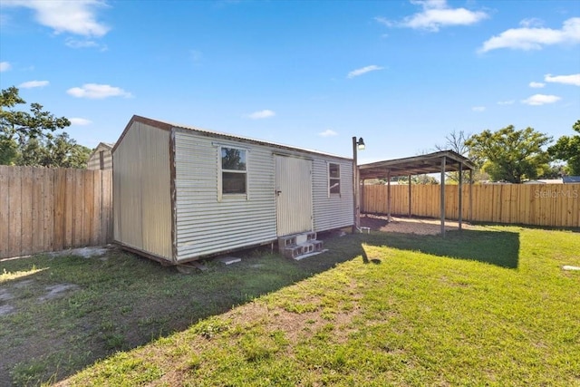 view of outbuilding with a carport, an outbuilding, and a fenced backyard