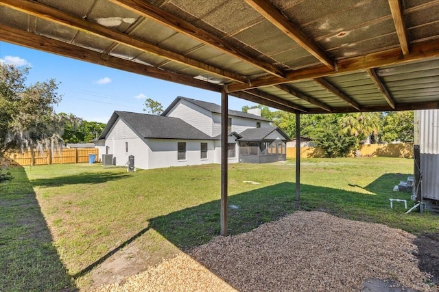 view of yard with fence, a sunroom, and central air condition unit