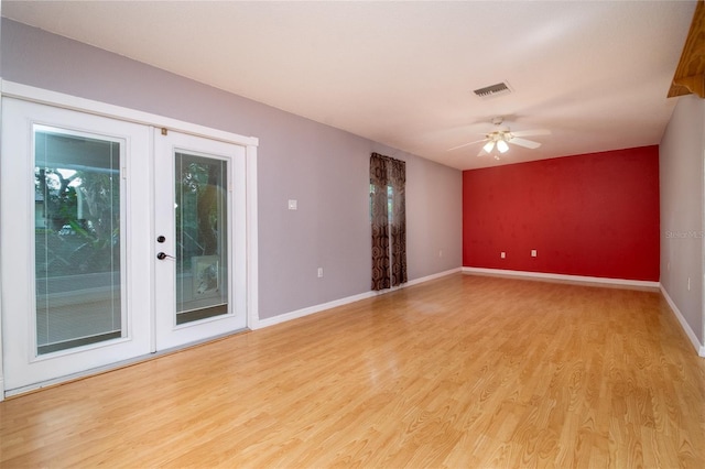 spare room featuring light wood finished floors, visible vents, baseboards, and a ceiling fan