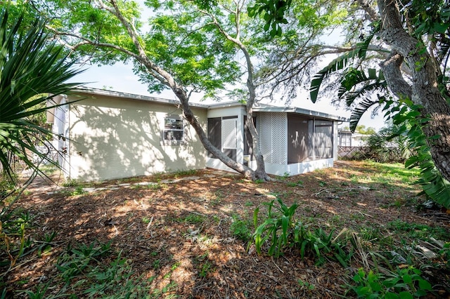 back of property with stucco siding and a sunroom