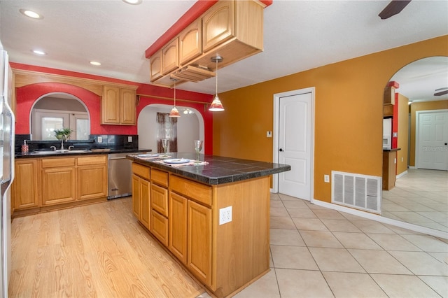 kitchen featuring arched walkways, dishwasher, a sink, and visible vents