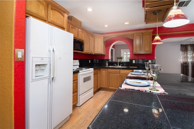 kitchen with arched walkways, a sink, white appliances, recessed lighting, and pendant lighting