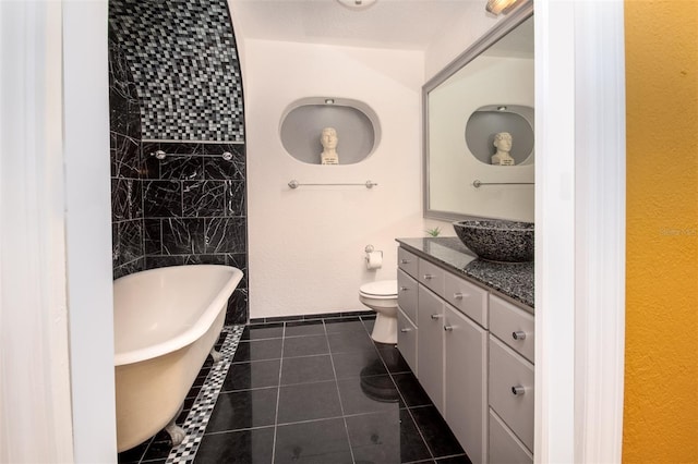 bathroom with tile patterned floors, toilet, a freestanding bath, and vanity