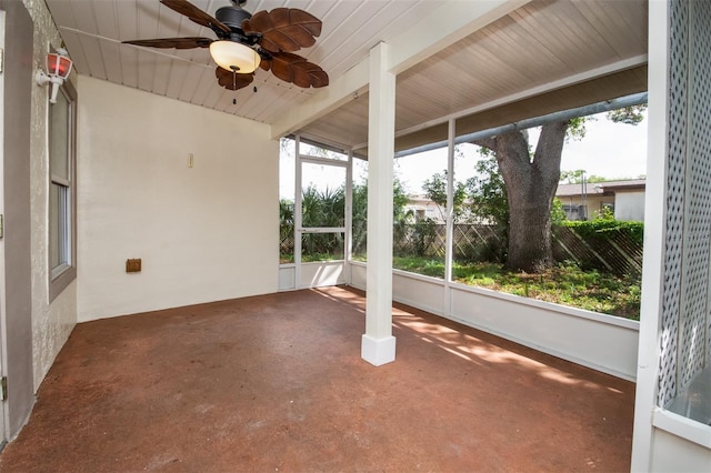 unfurnished sunroom with concrete flooring, beam ceiling, and a ceiling fan