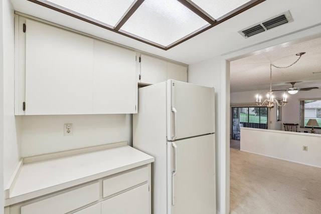456 Lakeview Dr Unit 5, Palm Harbor, FL 34683 - kitchen featuring freestanding refrigerator, light colored carpet, light countertops, a chandelier, and white cabinets