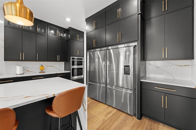 8720 Drummer Plank Dr, Wesley Chapel, FL 33545 - kitchen with dark cabinetry, light wood-style floors, appliances with stainless steel finishes, and tasteful backsplash