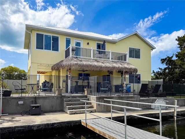 back of house featuring a balcony, a patio area, fence, stucco siding, and metal roof