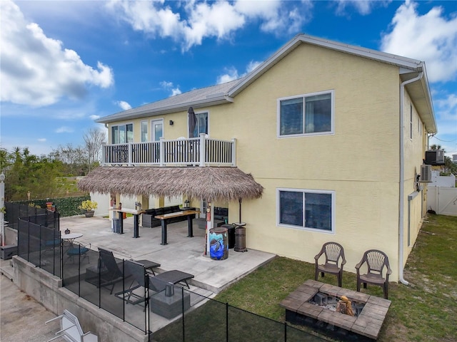 rear view of property with an outdoor fire pit, stucco siding, a patio, and a balcony