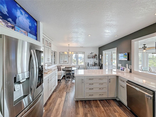kitchen with appliances with stainless steel finishes, a textured ceiling, light countertops, dark wood-style floors, and plenty of natural light