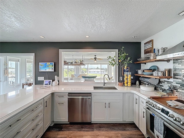 kitchen with appliances with stainless steel finishes, a sink, a textured ceiling, open shelves, and light countertops