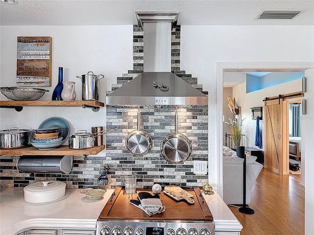 kitchen view of wall chimney exhaust hood, decorative backsplash, wood finished floors, and range