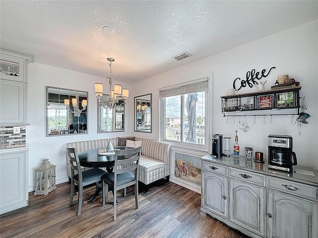 dining area with dark wood-style floors, a chandelier, healthy amount of natural light, and a textured ceiling