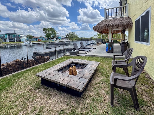 view of patio / terrace featuring an outdoor fire pit, a balcony, a water view, and a dock