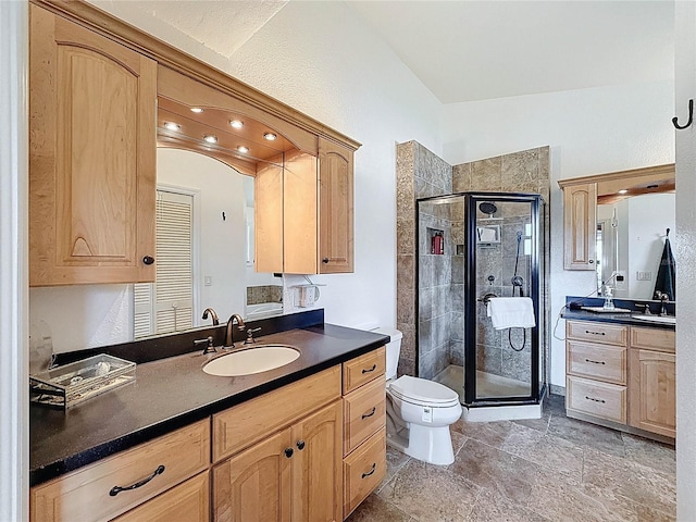 bathroom with a stall shower, toilet, and two vanities