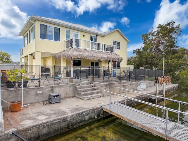 rear view of house featuring a balcony, a patio area, stucco siding, and fence