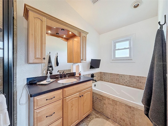 full bath with vaulted ceiling, a bath, and vanity