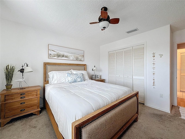 bedroom featuring light carpet, a closet, ceiling fan, and a textured ceiling