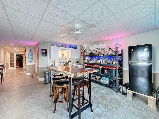 4116 Diaz Ct, Hernando Beach, FL 34607 - dining space featuring a ceiling fan, a paneled ceiling, a wall mounted air conditioner, concrete flooring, and bar area