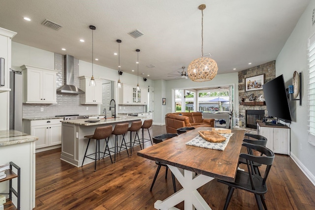 182 E Canal Dr, Palm Harbor, FL 34684 - dining space featuring dark wood-style flooring, visible vents, a stone fireplace, and baseboards