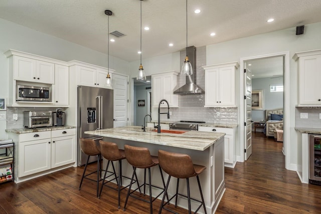 182 E Canal Dr, Palm Harbor, FL 34684 - kitchen featuring a breakfast bar, wall chimney range hood, a center island with sink, dark wood finished floors, and stainless steel appliances