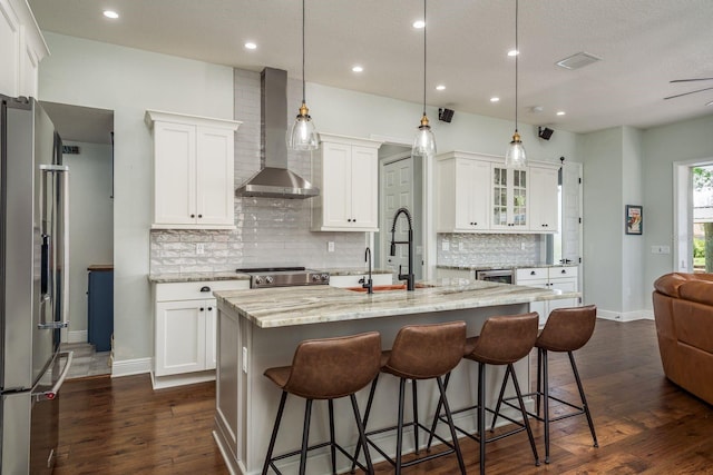 182 E Canal Dr, Palm Harbor, FL 34684 - kitchen featuring a kitchen breakfast bar, wall chimney range hood, white cabinets, stainless steel fridge, and a center island with sink