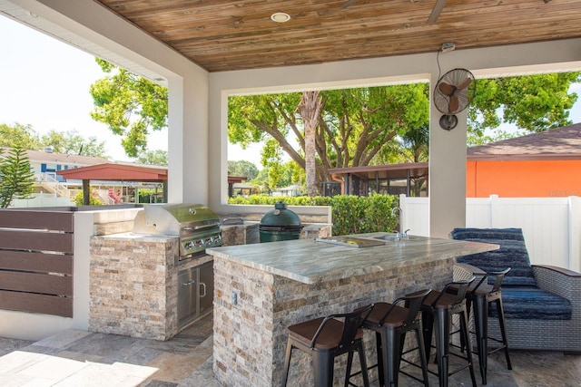 182 E Canal Dr, Palm Harbor, FL 34684 - view of patio / terrace featuring outdoor wet bar, a grill, a sink, fence, and exterior kitchen