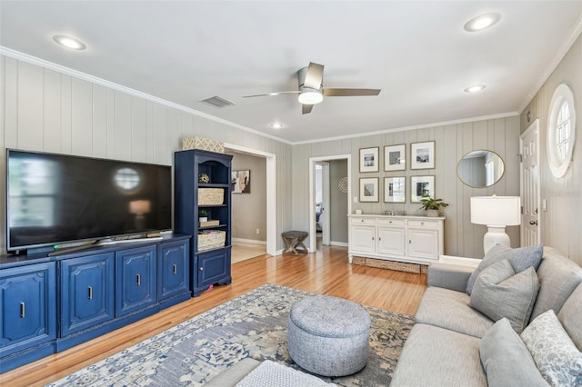 living area with light wood finished floors, baseboards, visible vents, ceiling fan, and ornamental molding