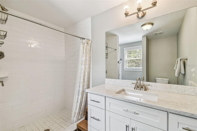 bathroom with toilet, vanity, a stall shower, and visible vents
