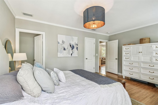 bedroom with dark wood-type flooring, visible vents, and crown molding