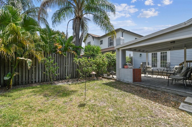 view of yard featuring a patio, fence, and french doors