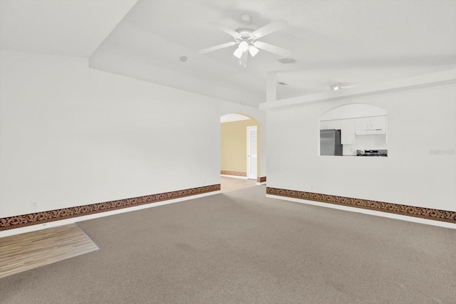 unfurnished room with lofted ceiling, carpet, baseboards, arched walkways, and ceiling fan