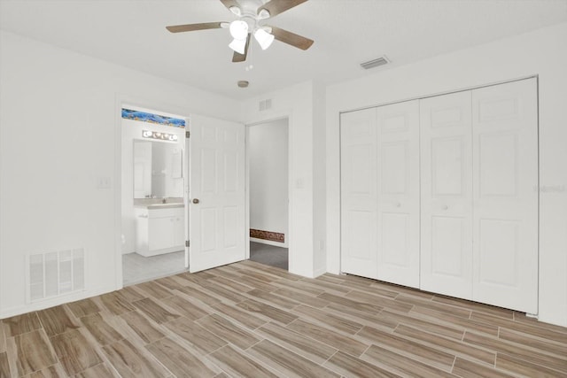 unfurnished bedroom with wood finish floors, a closet, and visible vents
