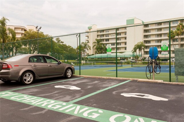 uncovered parking lot with fence and a tennis court