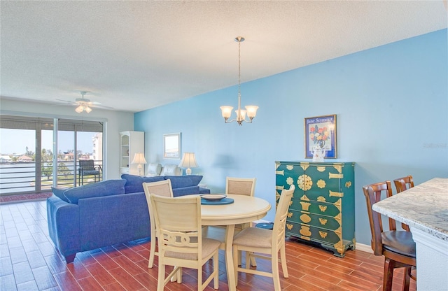 dining space with ceiling fan with notable chandelier, baseboards, wood finish floors, and a textured ceiling