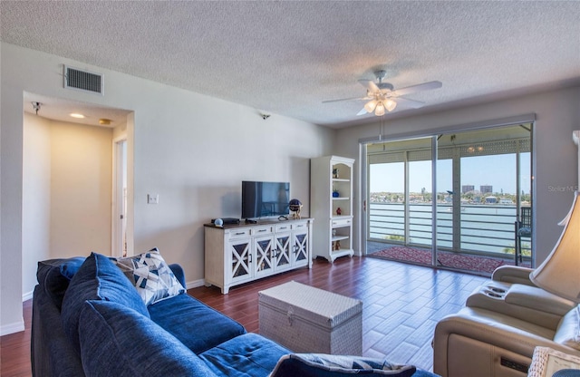 living area with ceiling fan, wood finished floors, visible vents, and a textured ceiling