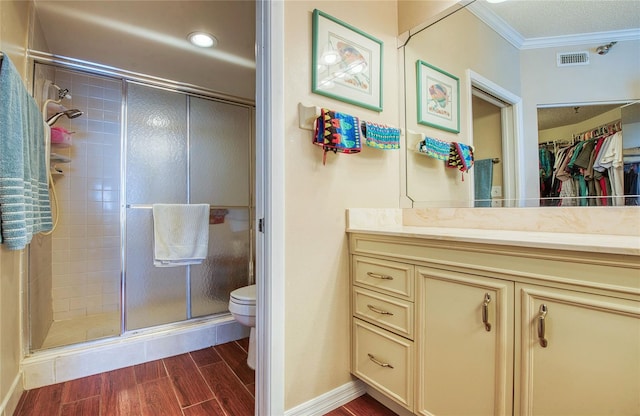 full bath featuring a shower stall, wood finished floors, toilet, vanity, and ornamental molding