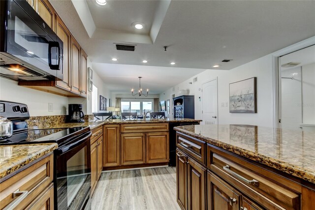 19925 Gulf Blvd Unit 502, Indian Shores, FL 33785 - kitchen with light stone countertops, visible vents, a peninsula, black appliances, and brown cabinets
