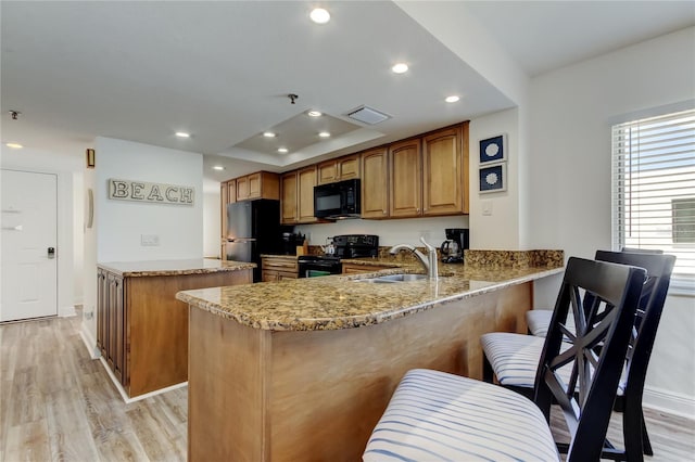 19925 Gulf Blvd Unit 502, Indian Shores, FL 33785 - kitchen featuring a sink, a peninsula, visible vents, light stone countertops, and black appliances