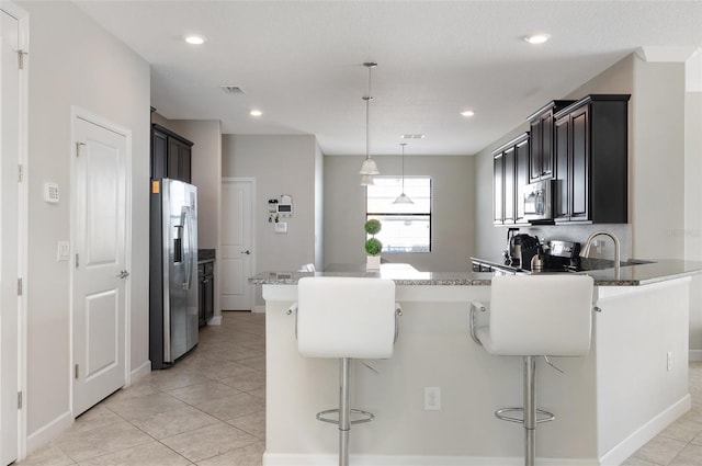 10008 Celtic Ash Dr, Ruskin, FL 33573 - kitchen with appliances with stainless steel finishes, a peninsula, a kitchen bar, light stone counters, and recessed lighting